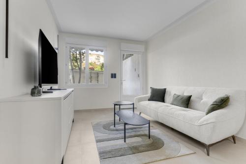 un salon blanc avec un canapé et une télévision dans l'établissement Modern 2 chambres avec jardin Martinez , 5 minutes from palais of festivals, à Cannes
