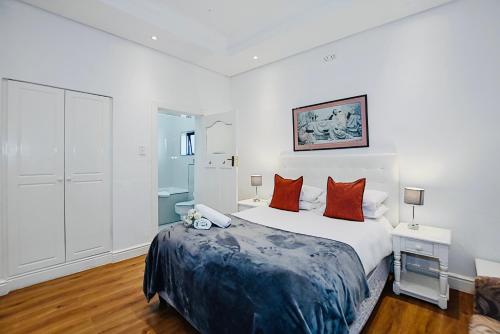 a white bedroom with a large bed with red pillows at Albatross Guest House Bantry Bay in Cape Town