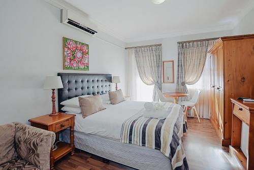 a bedroom with a bed and a table and a chair at Albatross Guest House Bantry Bay in Cape Town