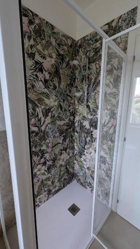 a shower in a bathroom with a floral wallpaper at Lake Garda Renovated Apartment in Torri del Benaco
