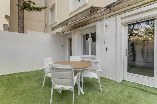 une table et des chaises sur une terrasse avec pelouse dans l'établissement Modern 2 chambres avec jardin Martinez , 5 minutes from palais of festivals, à Cannes