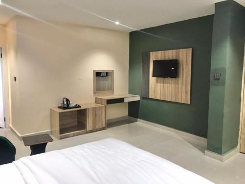 ウヨにあるSerene Garden Hotelsの緑の壁のベッドルーム1室(白いベッド1台付)