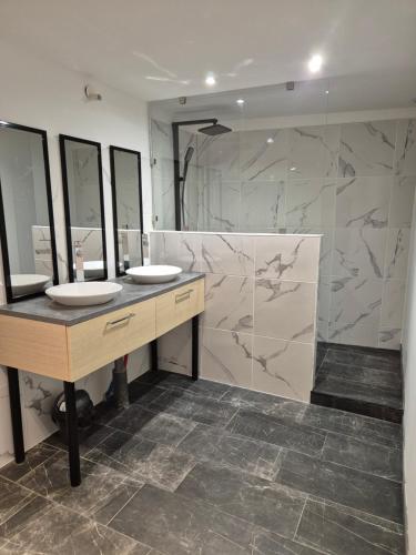 une salle de bain avec deux lavabos et un grand miroir dans l'établissement Le Gîte du Parc, à Roubia