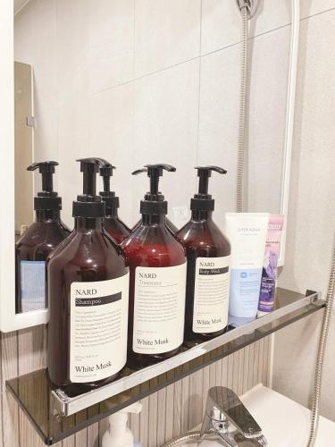 a shelf with four bottles of soap and a mirror at Golden Stay in Chuncheon