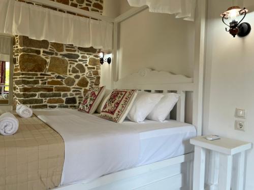 a white bed in a room with a brick wall at Rodakas Rooms-Glikeria in LivadhokhÃ³rion