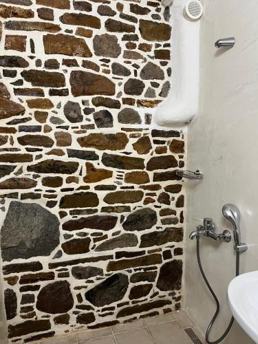 a stone wall in a bathroom with a shower at Rodakas Rooms-Glikeria in LivadhokhÃ³rion