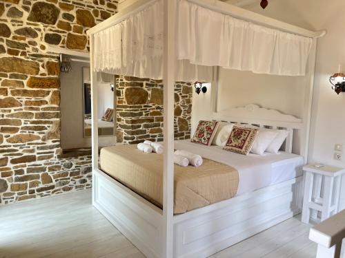a bedroom with a white canopy bed in a stone wall at Rodakas Rooms-Glikeria in LivadhokhÃ³rion