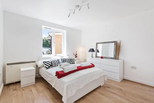 a white bedroom with a bed and a mirror at 2 Bed Flat, Dedicated workspace, Parking, 4KTV in London