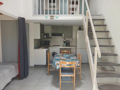 - une petite cuisine avec une table et un escalier dans une chambre dans l'établissement Petite villa coquette, au Cap d'Agde