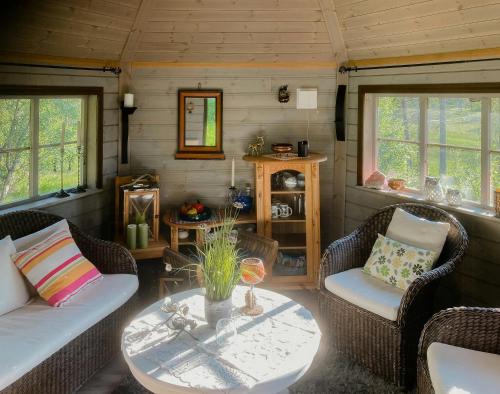 a living room with wicker chairs and a table at Log Cabin By Skoddeberg Lake In Tjeldsund in Grovfjord