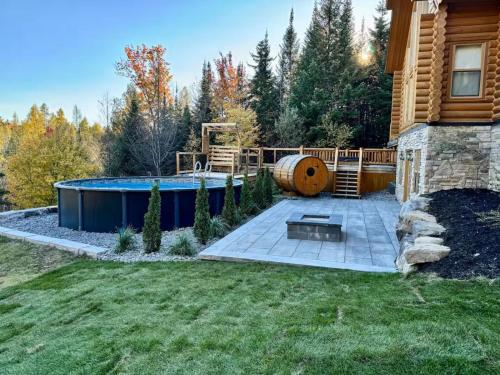 a backyard with a swimming pool and a house at Forest Getaway, Soak in the Spa, Sauna, Fireplace in Mille-Isles