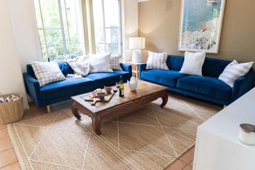 a living room with blue couches and a coffee table at Paradise Palms at Aanuka Resort Diggers Beach Quiet Villa in Coffs Harbour