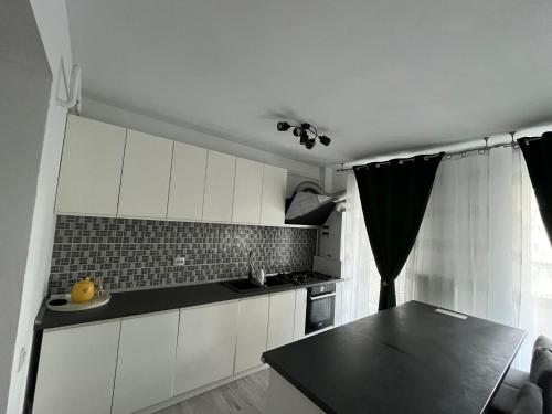 a kitchen with white cabinets and a black counter top at Nova One Apartment in Craiova