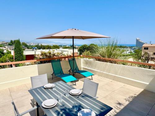 une table bleue avec des chaises et un parasol sur le toit dans l'établissement Les Cigales - Easy Home Booking, à Villeneuve-Loubet