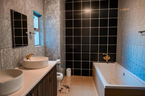 a bathroom with a sink and a tub and a toilet at Oceana Luxury Guesthouse in Windhoek