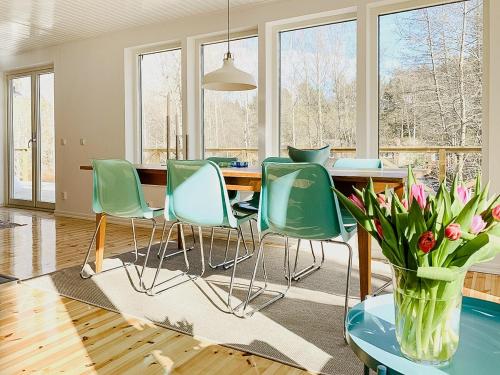 ein Esszimmer mit einem Tisch, Stühlen und einer Vase aus Blumen in der Unterkunft Charming House With Sea Proximity On Djurö in Djurhamn