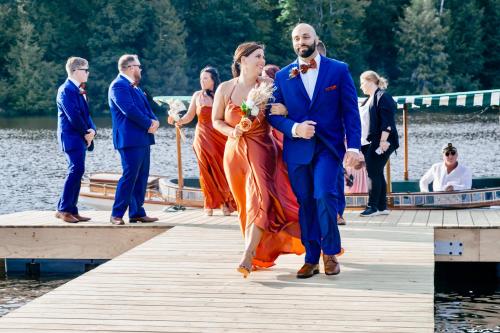 a bride and groom walking down a dock with their wedding party at Pocono Mountain Maple Farms in Newfoundland