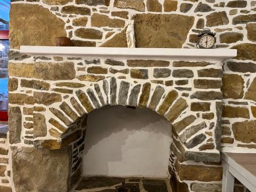 a stone fireplace with a clock on top of it at Rodakas Rooms-Aimilia in LivadhokhÃ³rion