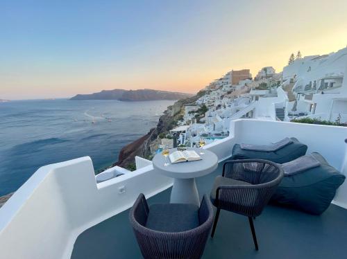 a table and chairs on a balcony overlooking the ocean at Èther suites Oia in Santorini