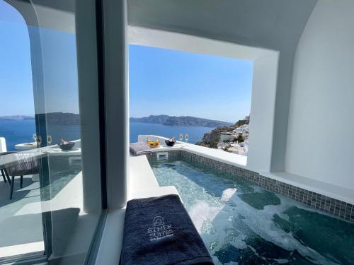 a swimming pool with a view of the water at Èther suites Oia in Santorini