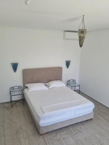 a white bedroom with a large bed with two tables at Deux Villas Privees Luxe avec Maison dAmis en Option a Hammamet in Yasmine
