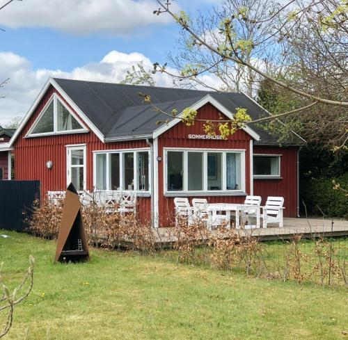 a red house with white chairs in front of it at Cozy Red Cottage By Kalø Vig With Seaview in Hornslet