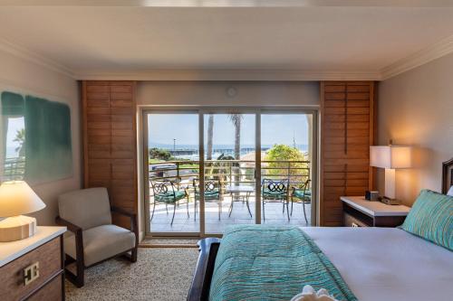 a bedroom with a bed and a balcony with a view at Pacific Terrace Hotel in San Diego