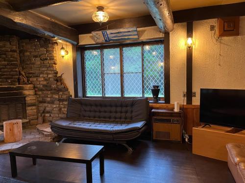 a living room with a leather couch and a tv at Matsunoki-tei in Otari