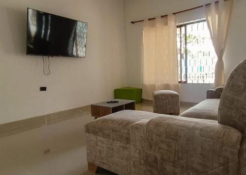 a living room with a couch and a flat screen tv at Chazze House in Santa Marta