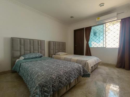 a bedroom with two beds and a window at Chazze House in Santa Marta