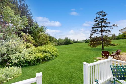 a yard with a white fence and chairs on a lawn at The Village House in Manchester