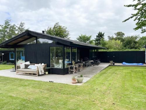 a black building with a deck in a yard at Family Idyll Near Kattegat In Tisvilde in Tisvildeleje