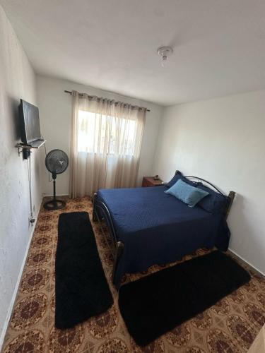 a bedroom with a blue bed and a window at Suíte no centro in Saquarema