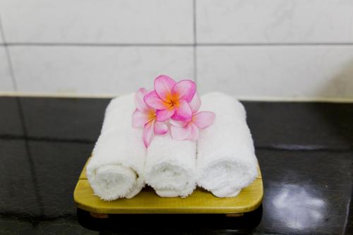 a pink flower sitting on a pile of towels at Moatoga Hotel in Apia