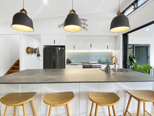 a kitchen with a counter and four stools at White Pandanus in Horseshoe Bay
