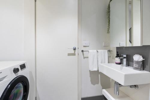 a white bathroom with a washing machine and a sink at The South Yarra Jewel in Melbourne