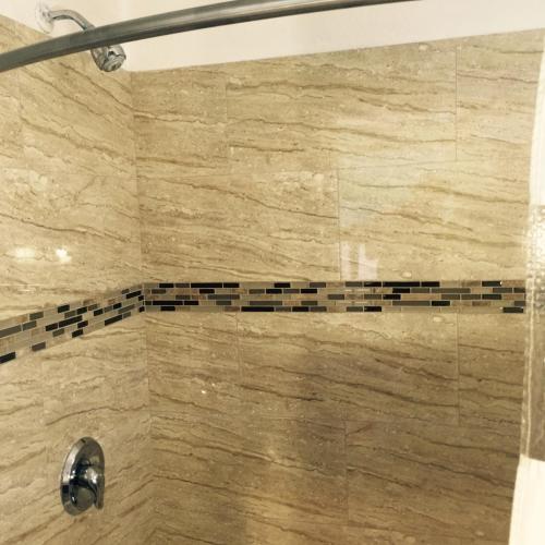 a bathroom with a shower with a beige and black tile at Crenshaw Inn Motel in Los Angeles