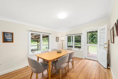 une salle à manger avec une table et des chaises en bois dans l'établissement Cutlers Cottage, à Bombah Point