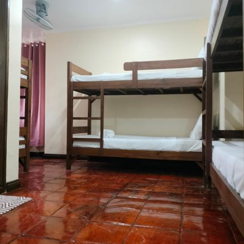 a room with three bunk beds and a tile floor at Makabata Guesthouse & Cafe in Manila