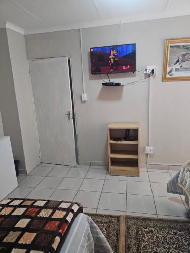 a bedroom with a tv on the wall and a bed at MP Stop Guest House in Rustenburg