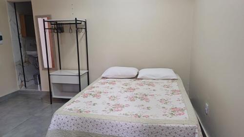 a bed in a white room with a bedspread on it at Stúdio em ótima localização in Santarém