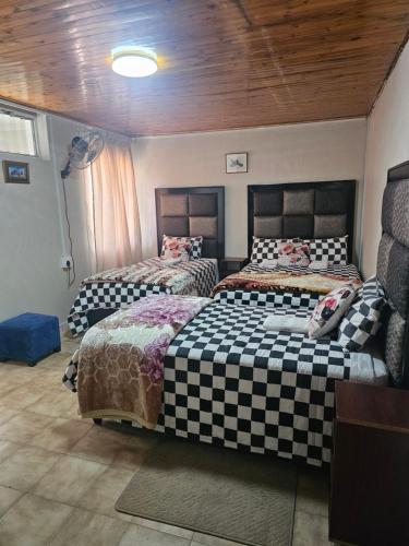 a bedroom with two beds and a wooden ceiling at MP Stop Guest House in Rustenburg