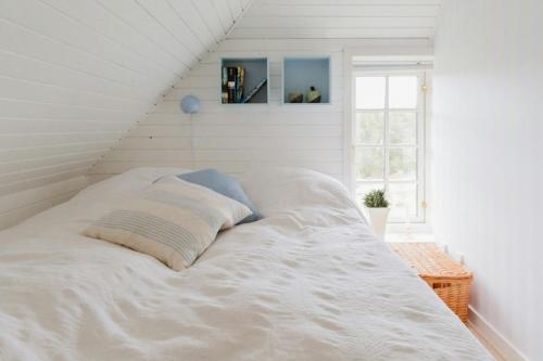 a white bed in a white room with a window at View Of Nyminde Stream And Dunes in Nymindegab