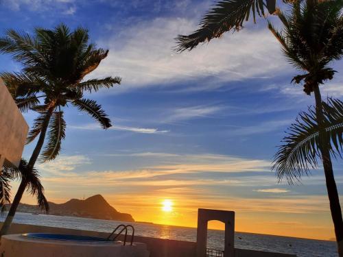 a view of the sunset from a beach with palm trees at House on the Beach in Manzanillo