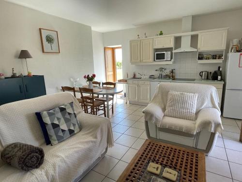 une cuisine avec un canapé, des chaises et une table dans l'établissement Gîte confortable au cœur des vignes avec terrasse, vélos, WiFi et équipements bébé à 17 km de Nantes - FR-1-306-808, à Châteauthébaud