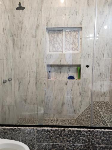 a shower with a glass door in a bathroom at House on the Beach in Manzanillo