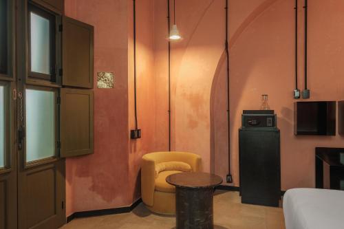 a living room with a yellow chair and a table at Pug Seal Oaxaca in Oaxaca City