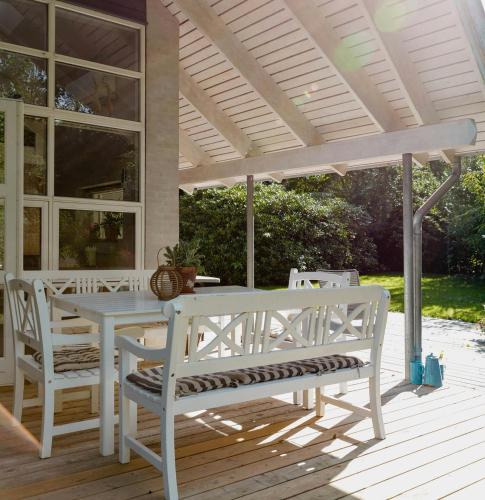 a white table and chairs on a porch with a pergola at An Intimate Get-Away By The Sandvig Bay in Haderslev