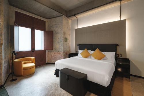 a bedroom with a large white bed and a chair at Pug Seal Oaxaca in Oaxaca City
