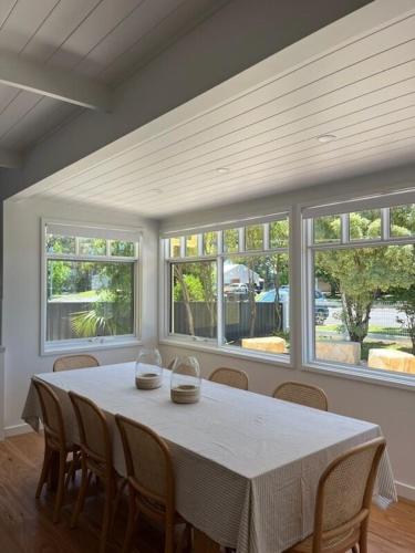 a dining room with a table with chairs and windows at Daffodil on Owen in Huskisson